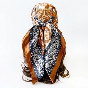 Detail view of large paisley silk scarf tied as a headwrap in orange and navy blue