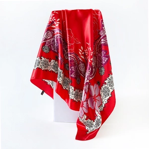 Close-up of red paisley satin scarf draped on a white pedestal with silk-like sheen