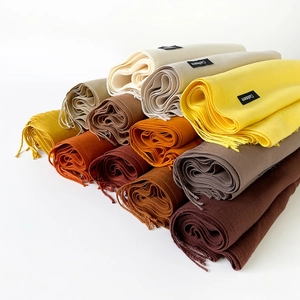 Stacked soft cashmere scarves featuring tassel details in various warm autumn colors