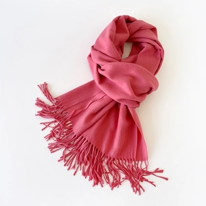 Detailed close-up of soft rose pink faux cashmere scarf with fringe tassels on white background