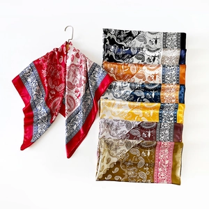 Detail of silk-like satin square scarves featuring classic paisley and geometric patterns