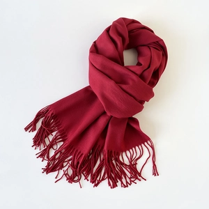 Close-up of a burgundy cashmere-like scarf showing soft texture and tassel fringe detail