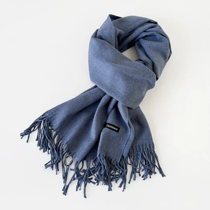 Close-up of blue cashmere scarf with elegant tassels and stitched brand label detail