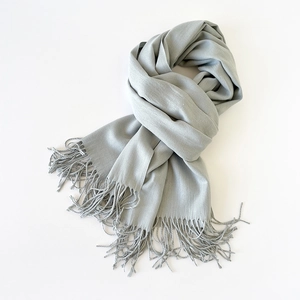 Detail shot of light grey scarf featuring smooth texture and fine fringe tassels