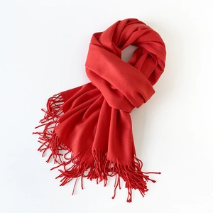 Detailed view of soft red faux cashmere scarf with elegant fringe trim on white background