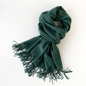 Detailed view of soft dark green cashmere-feel scarf with elegant long fringe tassels
