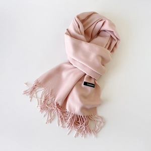 Close-up of pink cashmere scarf featuring soft fabric texture and delicate fringe details