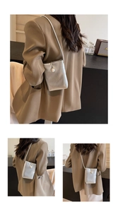 Detailed view of mini silver metallic bag featuring a large pearl button and slim shoulder strap