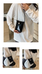 Detail of a black mini crossbody bag featuring a large pearl embellishment and glossy finish