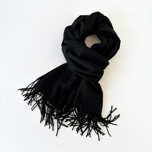 Detail shot of the fine fringe craftsmanship on a soft black cashmere-like scarf