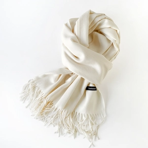 Close-up of the cream cashmere scarf texture showing fine weaving and soft fringe details