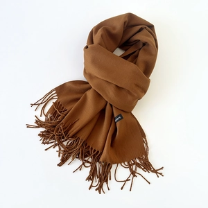 Detail shot of caramel brown cashmere scarf showing soft texture and tassel edges