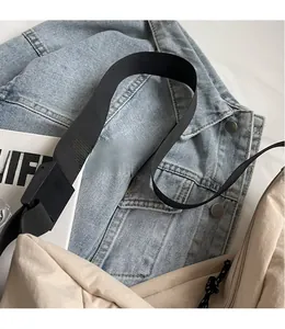 Detail of adjustable black nylon strap and plastic buckle on beige canvas crossbody bag
