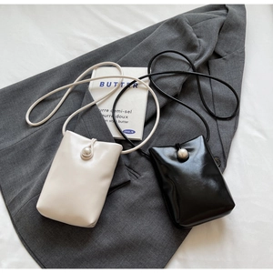 Detail of mini leather crossbody bags with large pearl buckle in black and beige