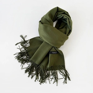Close-up of olive green cashmere scarf texture featuring fine fringe and fabric label