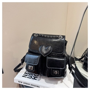 Detail of black glossy leather backpack with heart patch and silver chain strap