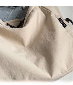 Detailed macro view of lightweight beige nylon fabric with drawstring and woven logo label