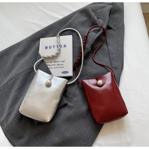 Detail of silver and burgundy mini crossbody bags with pearl buckles and woven straps