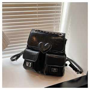 Detail of black PU backpack featuring heart patch, chain handle and silver twist locks