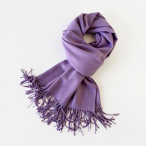 Detailed texture of purple cashmere-like scarf with fringe edges on white background