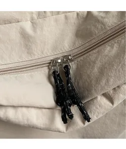 Macro shot of silver metal zippers and woven lanyards on a beige canvas shoulder bag