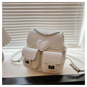 Detail of cream white leather backpack featuring heart embossed pattern and chain strap