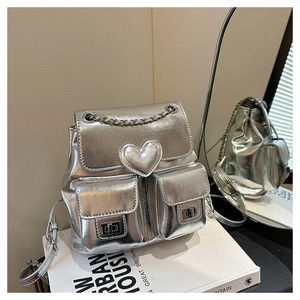 Detail of silver metallic mini backpack with heart-shaped decor and metal chain straps