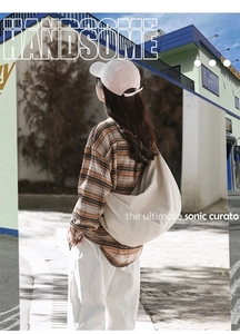 Outdoor shot of a model wearing a large beige crescent canvas crossbody bag with wide strap