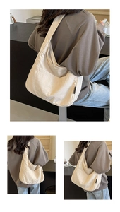 Detail view of a beige oversized canvas hobo bag showing side straps and branding
