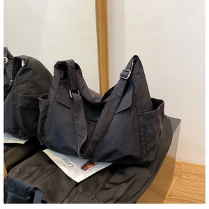 Detail view of the durable black nylon fabric and adjustable wide strap on the crossbody bag