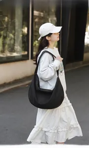 Outdoor street shot of large black nylon crescent shoulder bag on a female model