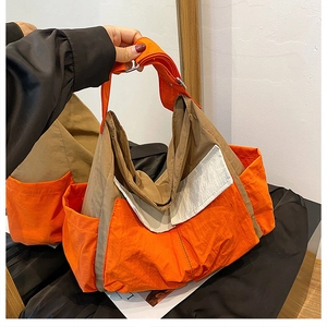 Detail of orange and khaki nylon tote bag showing side pockets and webbing straps