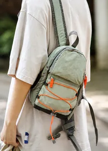 Zaino outdoor verde chiaro con corde elastiche arancioni mostrato in ambiente naturale