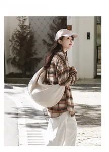 Detailed side view of off-white nylon hobo bag carried by model in casual outdoor setting