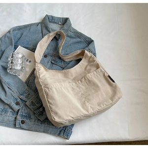 Close-up of cream canvas hobo bag with front pockets on a minimalist lifestyle setting