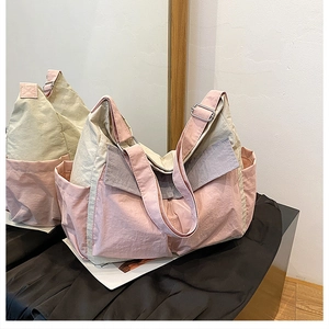 Detail of pink and beige nylon crossbody bag featuring adjustable metal buckle and side pocket