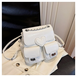 Detail of white glossy mini backpack featuring a heart flap and silver chain handle