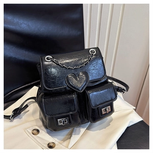 Detail of black oil wax PU leather backpack featuring heart patch and silver chain accents