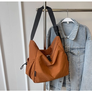 Detailed shot of brown canvas crossbody bag with adjustable strap and drawstring side pocket