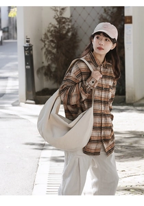 Detail of beige crescent canvas crossbody bag with textured fabric in outdoor street style