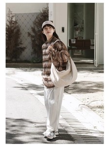 Woman carrying a large off-white nylon crescent shoulder bag in an outdoor street setting