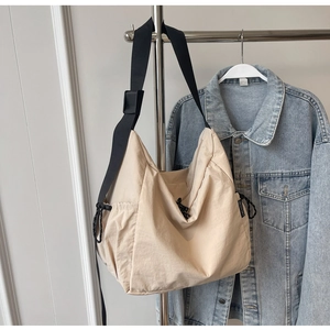 Detail of beige large capacity crossbody bag with black adjustable wide strap