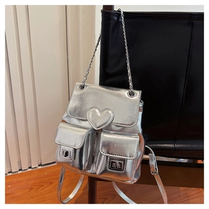 Detail of silver metallic mini backpack with heart patch and chain straps