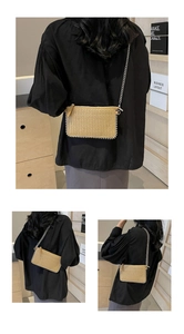 Detail of straw woven crossbody bag featuring elegant pearl trim and metal chain strap