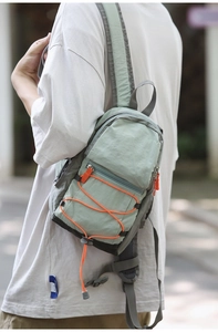Vista dettagliata della borsa da petto in nylon verde menta con cordino arancione e zip