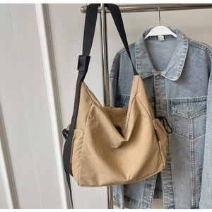 Detail view of khaki nylon messenger bag with adjustable wide strap and woven zipper pull