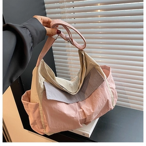 Detailed close-up of a high-capacity nylon tote bag with pink and beige color-blocking