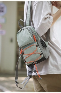 Borsa a tracolla outdoor verde menta e grigio con cordino elastico arancione sul modello