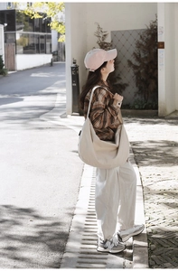 Detail of off-white minimalist nylon hobo bag with a wide strap in an outdoor setting