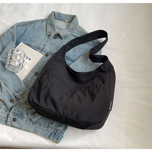 Detail of quilted black nylon shoulder bag with brand label on denim jacket background